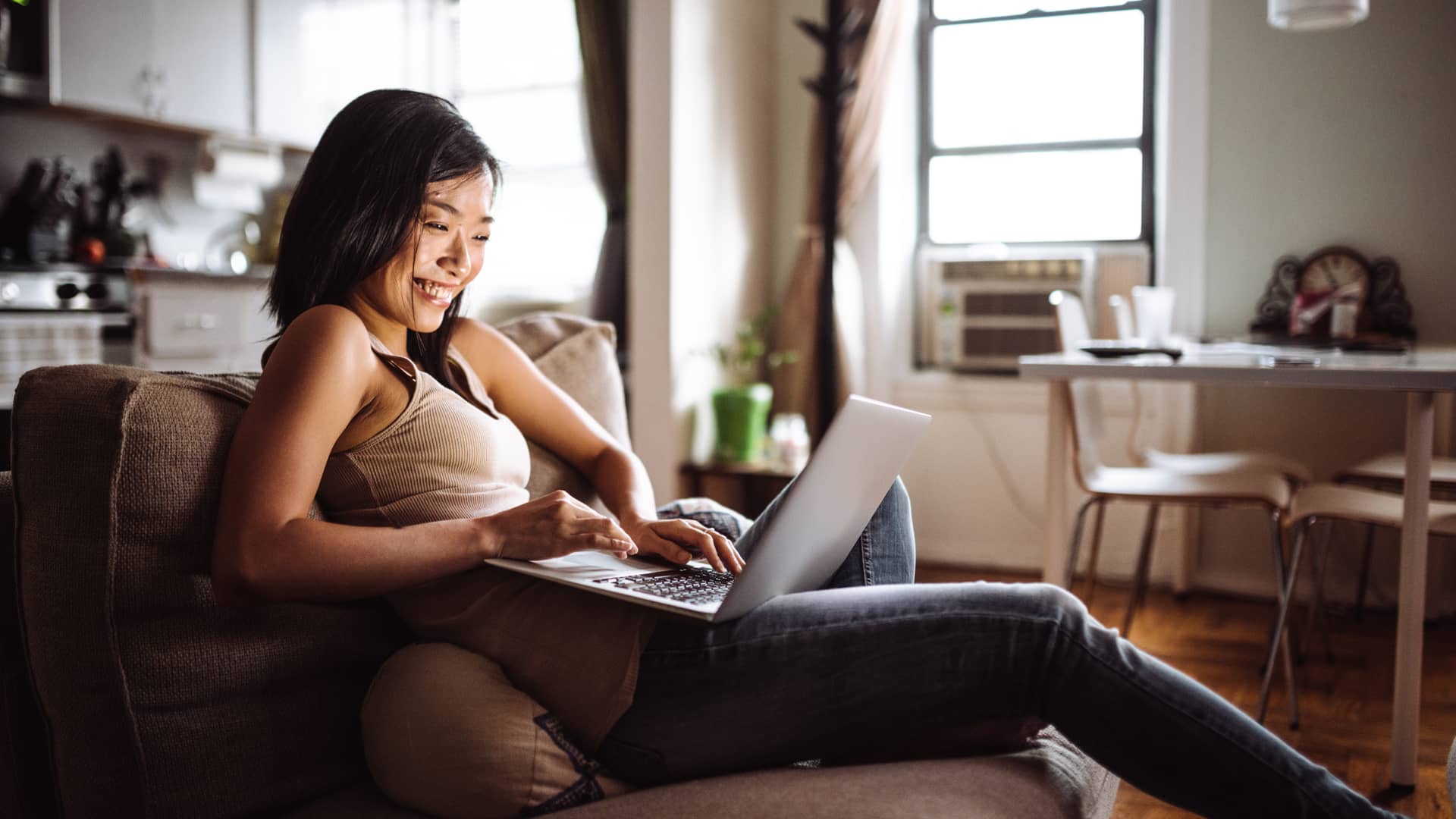 Mujer sonriente en su domicilio usando su portátil con paquete de internet y tv de axtel