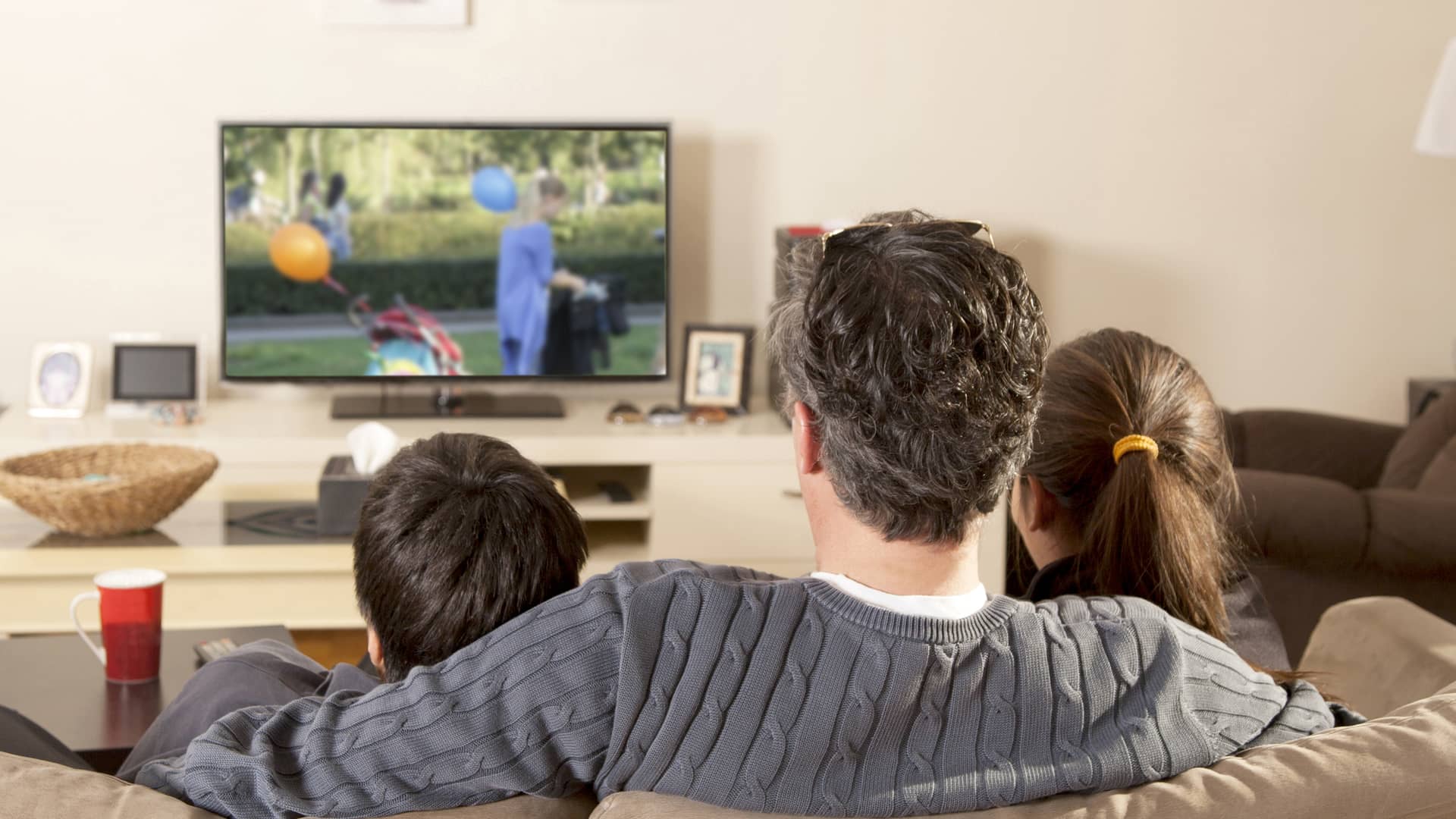 padre viendo la tele con sus dos hijos gracias a la instalacion de la caja digital de tv de megacable