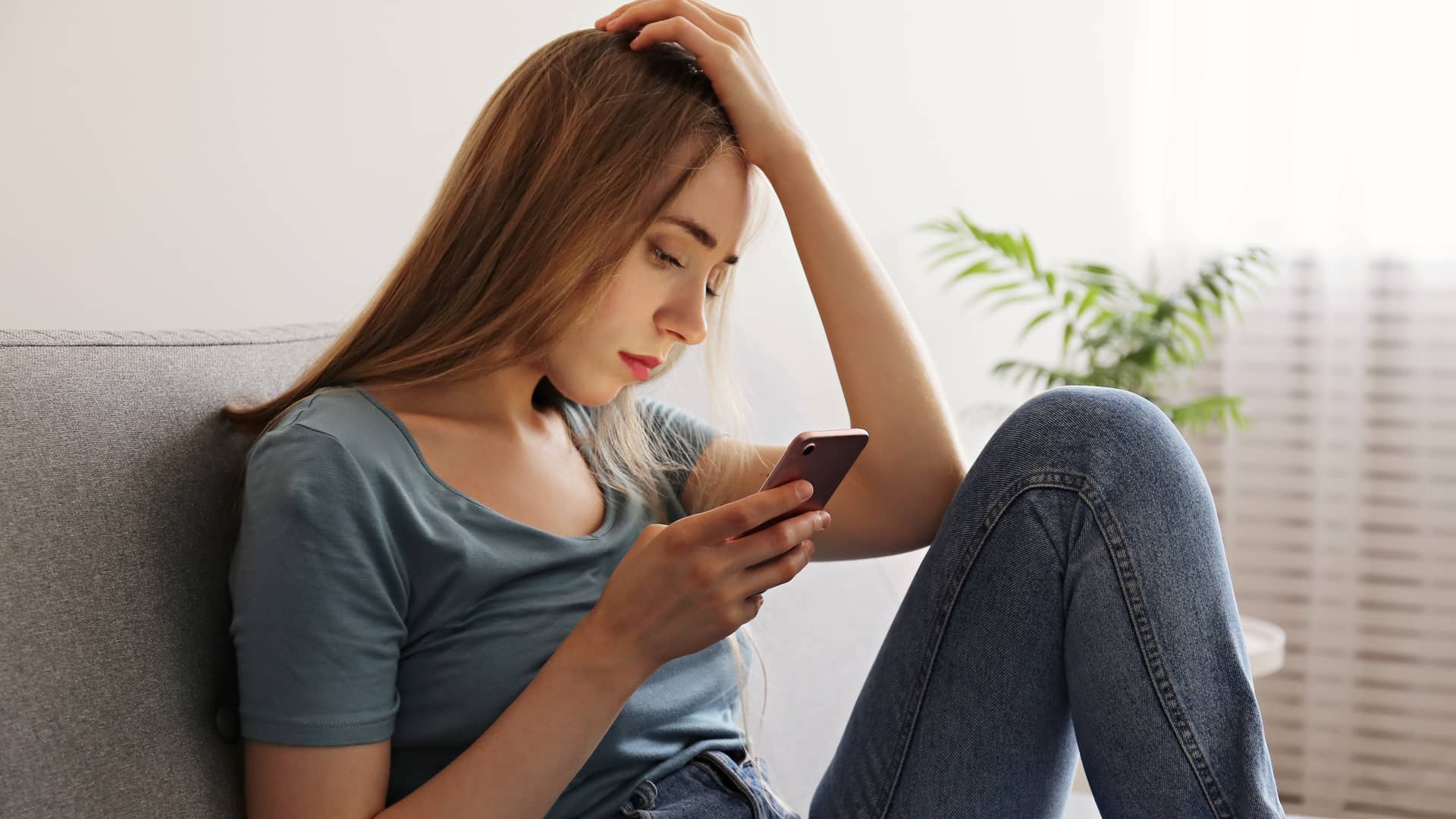 mujer triste con su celular a causa de las fallas en clientes de telmex