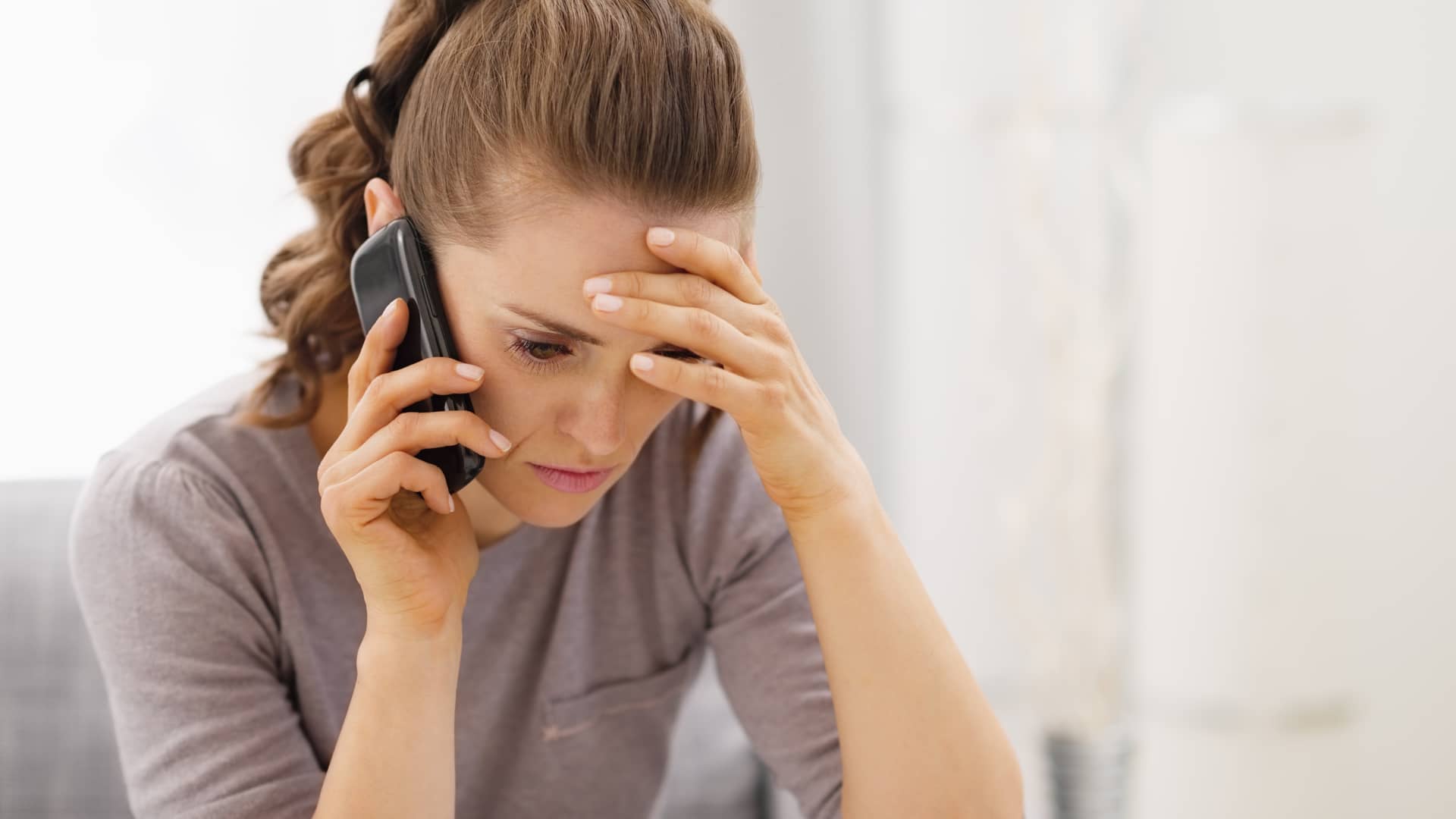 mujer enfadada con su celular que tratatr de reportar un fallo como cliente de telmex