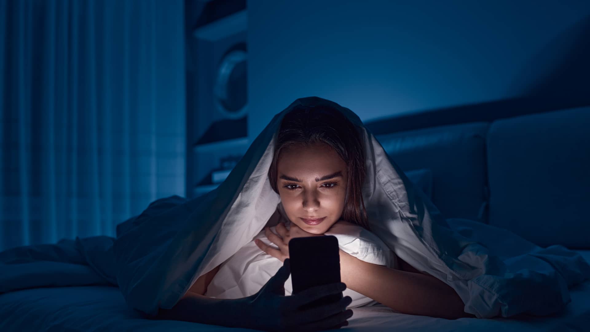 joven en la cama utilizando su celular con una nueva tarifa flex de unefon